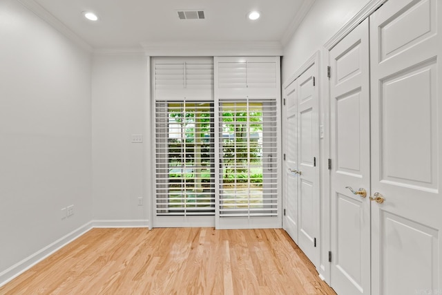 empty room featuring ornamental molding and light wood-type flooring