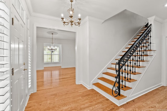 foyer featuring ornamental molding, a chandelier, and light wood-type flooring