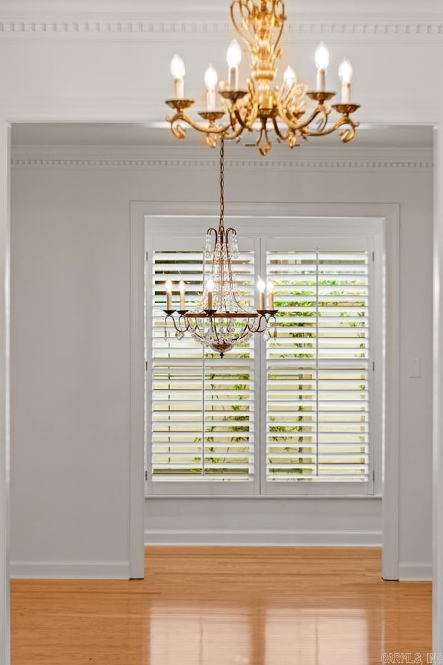 unfurnished dining area with hardwood / wood-style flooring, an inviting chandelier, and crown molding