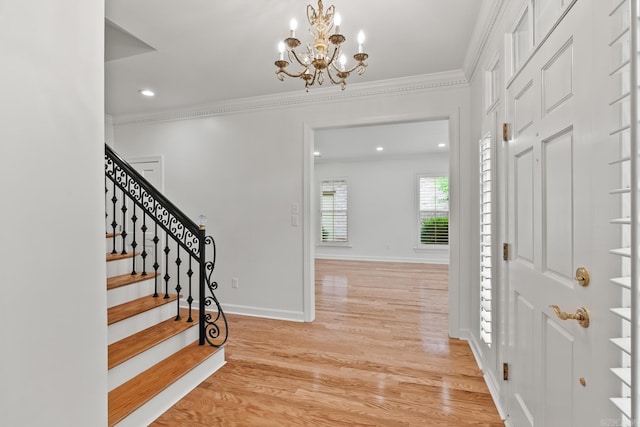 entrance foyer with ornamental molding, light hardwood / wood-style flooring, and a notable chandelier