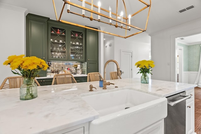 kitchen featuring light stone countertops, pendant lighting, green cabinets, tasteful backsplash, and sink