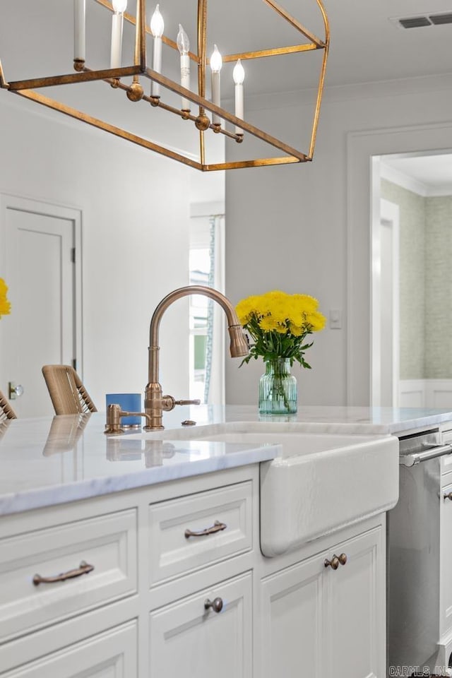 interior space with ornamental molding, white cabinetry, stainless steel dishwasher, and sink