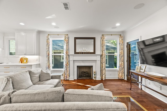 living room with plenty of natural light, crown molding, and dark wood-type flooring