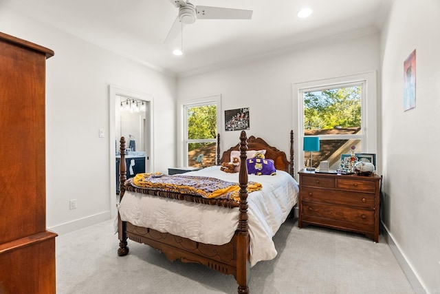 bedroom featuring ceiling fan, connected bathroom, multiple windows, and light carpet