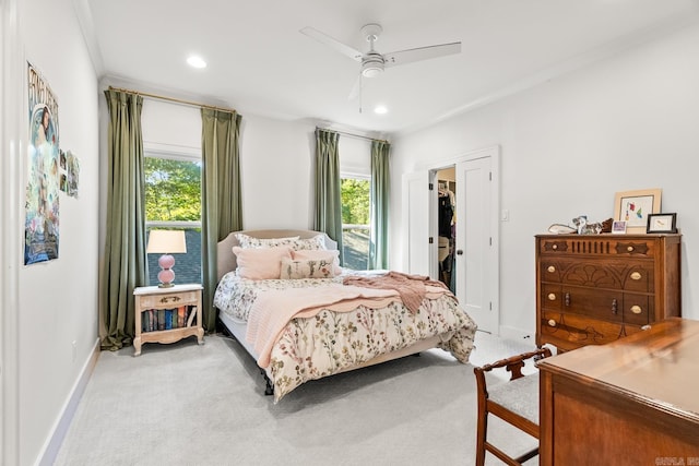 bedroom featuring ceiling fan, a walk in closet, light carpet, and crown molding