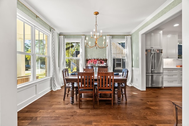 dining space featuring dark wood-type flooring, crown molding, and a chandelier