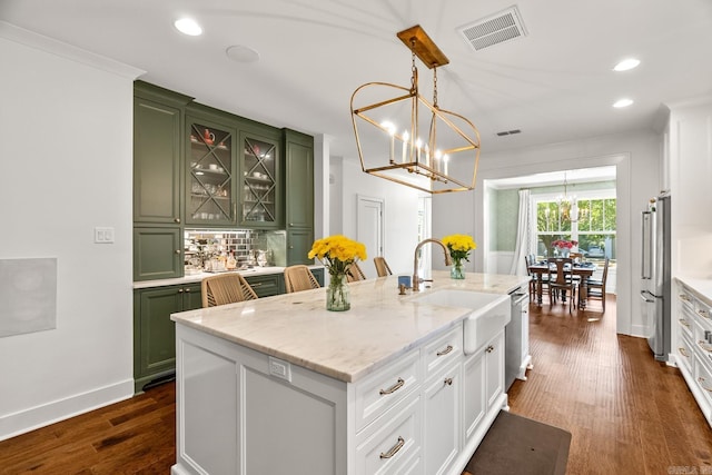 kitchen featuring a center island with sink, hanging light fixtures, stainless steel appliances, dark hardwood / wood-style flooring, and green cabinets