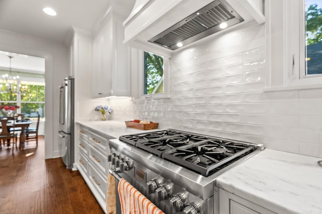 kitchen featuring appliances with stainless steel finishes, light stone countertops, dark wood-type flooring, white cabinets, and wall chimney range hood