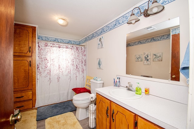 bathroom with toilet, vanity, and walk in shower