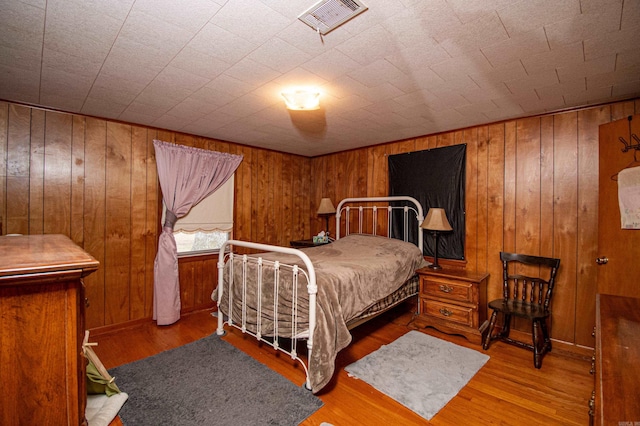 bedroom featuring hardwood / wood-style floors and wood walls