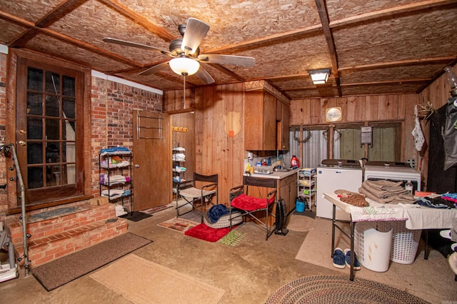 kitchen featuring washing machine and clothes dryer, ceiling fan, and wood walls