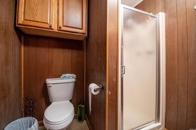 bathroom with toilet, an enclosed shower, and wood walls