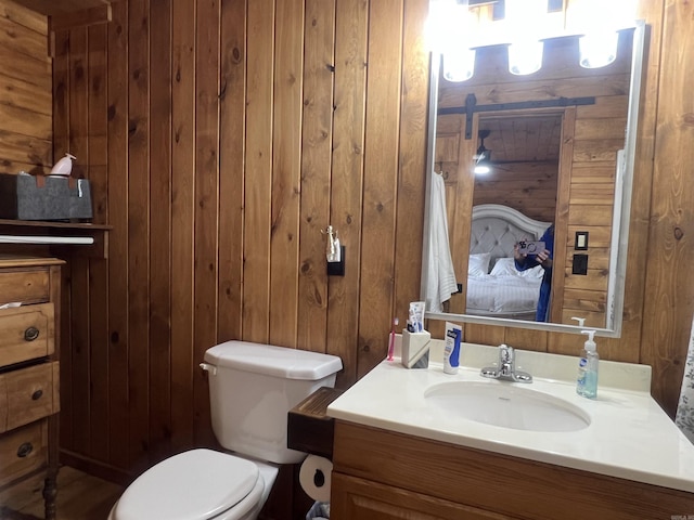 bathroom featuring vanity, toilet, and wood walls