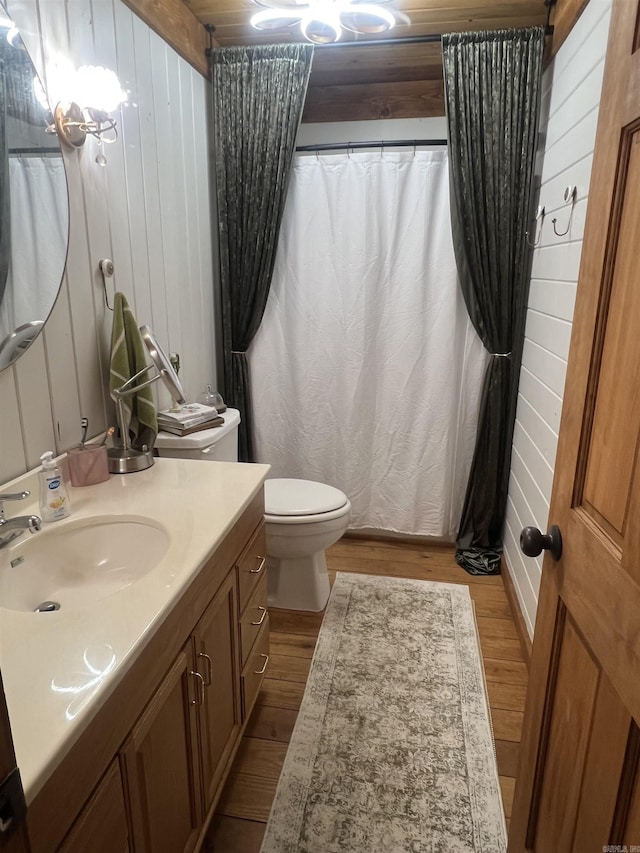 bathroom featuring toilet, wood finished floors, vanity, and wood walls