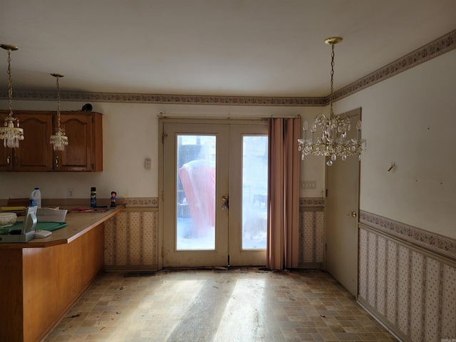 kitchen featuring decorative light fixtures, kitchen peninsula, a notable chandelier, and a healthy amount of sunlight