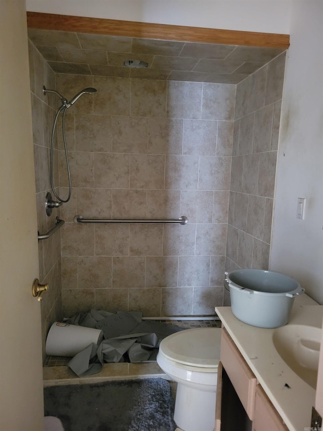 bathroom featuring a tile shower, vanity, and toilet