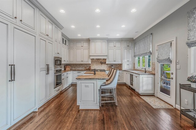 kitchen featuring sink, a kitchen bar, a kitchen island, dark hardwood / wood-style flooring, and appliances with stainless steel finishes