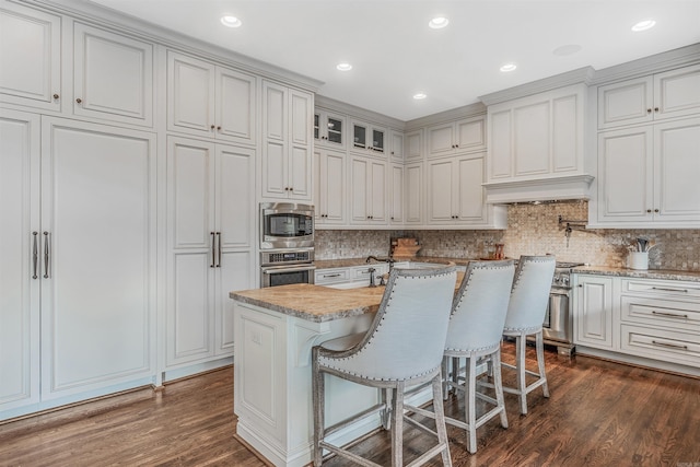 kitchen with a kitchen island, white cabinets, appliances with stainless steel finishes, and dark hardwood / wood-style floors