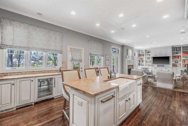 kitchen featuring sink, an island with sink, beverage cooler, dark hardwood / wood-style flooring, and a breakfast bar