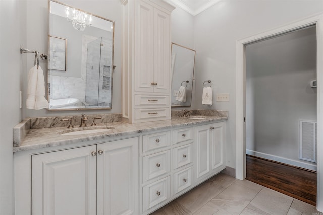 bathroom featuring vanity, an inviting chandelier, ornamental molding, and a bath