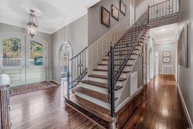 entryway featuring an inviting chandelier, french doors, crown molding, and dark hardwood / wood-style floors