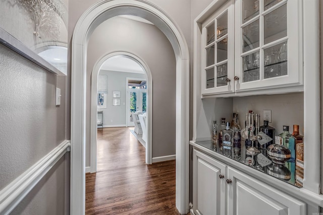 bar with white cabinetry and dark wood-type flooring