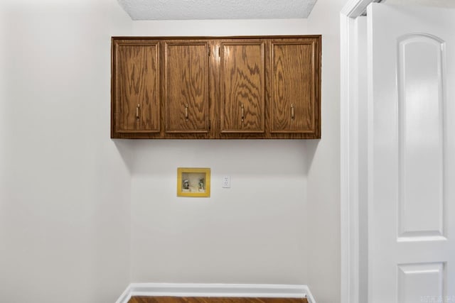 laundry room with hookup for a washing machine, cabinets, and a textured ceiling