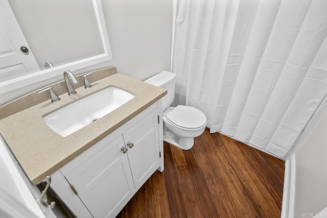 bathroom with toilet, vanity, and hardwood / wood-style floors