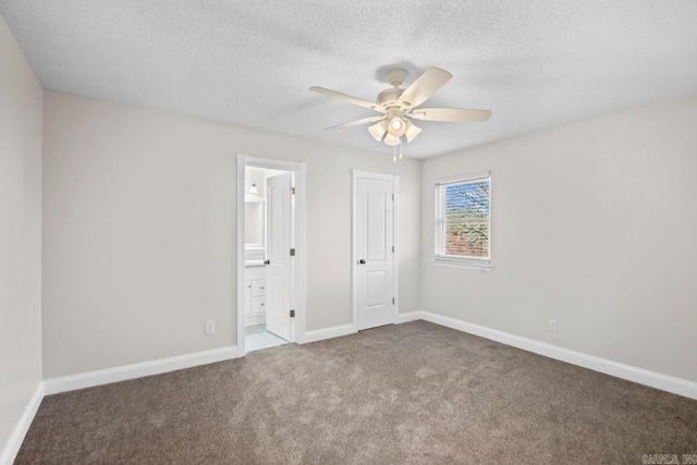 unfurnished bedroom with a textured ceiling, carpet, ceiling fan, a closet, and ensuite bath