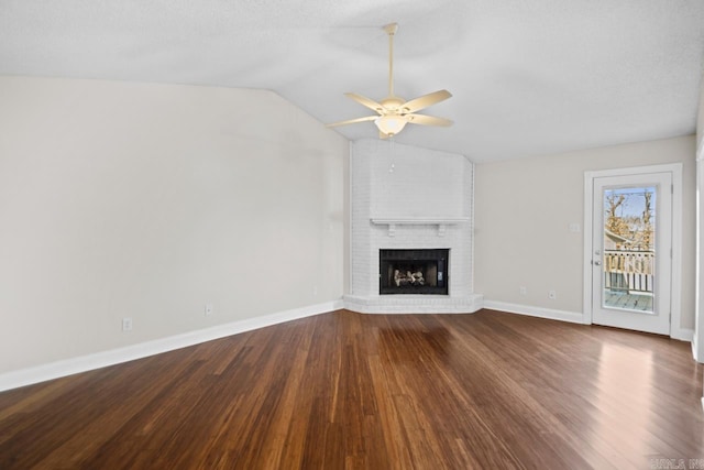 unfurnished living room with ceiling fan, vaulted ceiling, a fireplace, and wood-type flooring