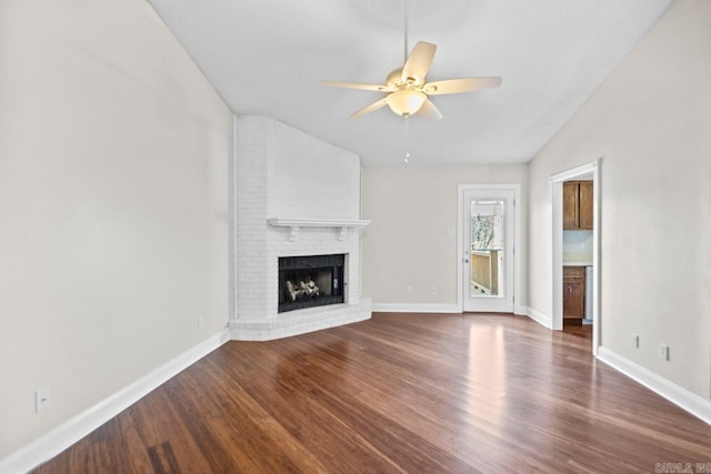 unfurnished living room featuring ceiling fan, a brick fireplace, vaulted ceiling, and hardwood / wood-style flooring