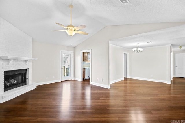 unfurnished living room with vaulted ceiling, dark hardwood / wood-style floors, a fireplace, a textured ceiling, and ceiling fan with notable chandelier