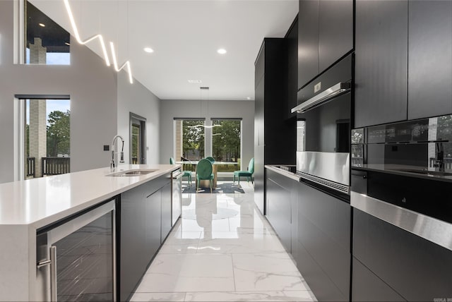 kitchen with sink, oven, decorative light fixtures, and beverage cooler