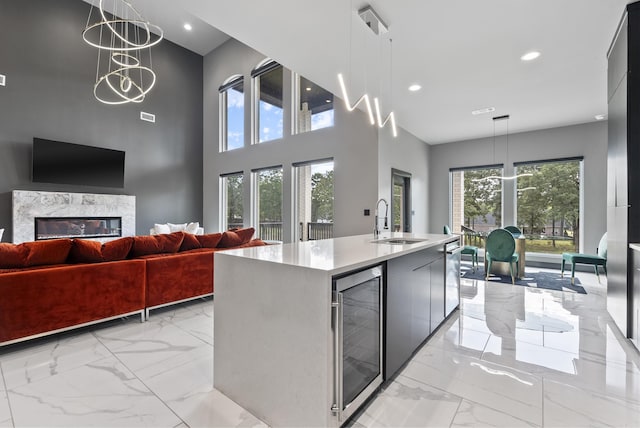 kitchen with a kitchen island with sink, a chandelier, wine cooler, hanging light fixtures, and sink