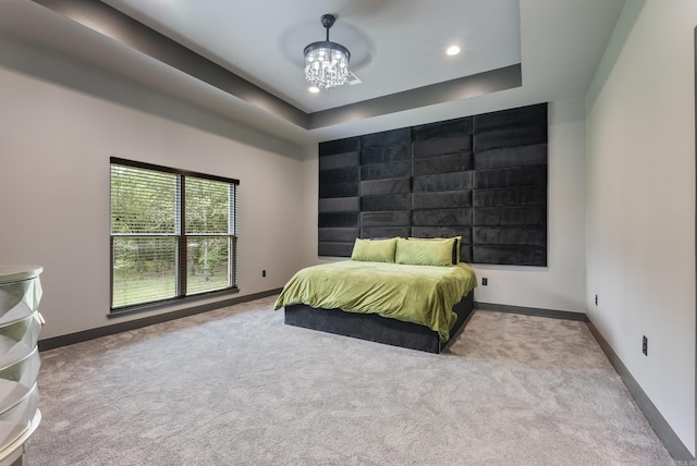 bedroom featuring light colored carpet, a chandelier, and a tray ceiling