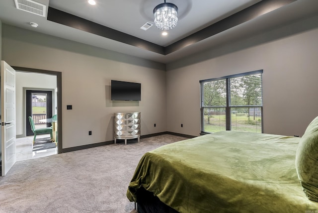 carpeted bedroom featuring a notable chandelier, multiple windows, and a raised ceiling