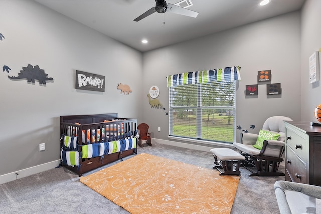 bedroom featuring a crib, light carpet, and ceiling fan