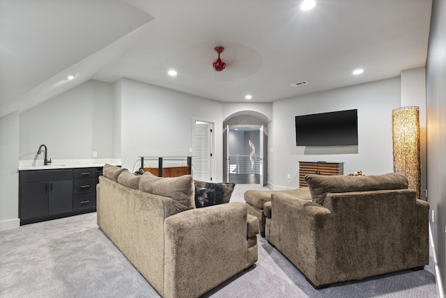 carpeted living room featuring sink and lofted ceiling