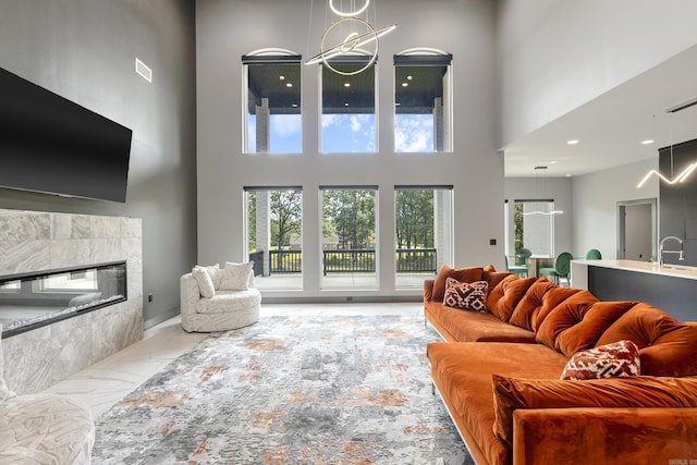 living room featuring a towering ceiling, a fireplace, and sink