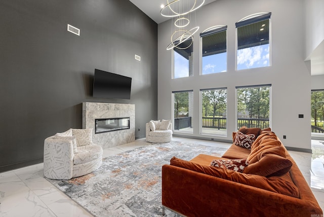 living room with a towering ceiling, a fireplace, and a notable chandelier