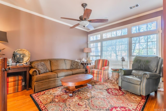 living room with ceiling fan, a healthy amount of sunlight, light wood-type flooring, and crown molding