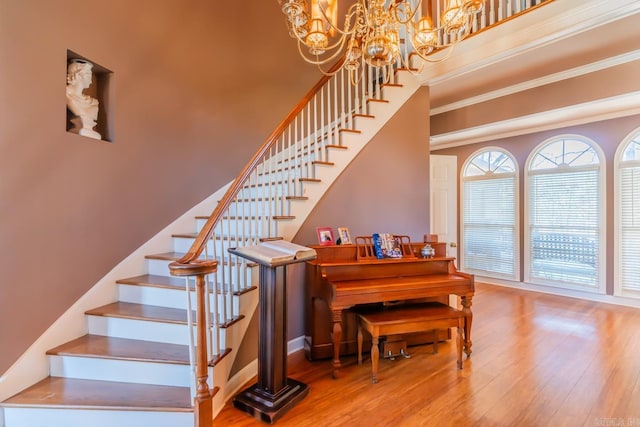 stairway featuring hardwood / wood-style floors, an inviting chandelier, and ornamental molding