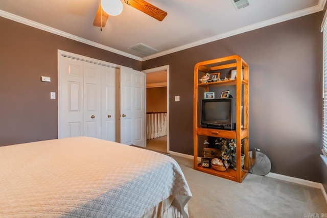 carpeted bedroom with ceiling fan, ornamental molding, and a closet