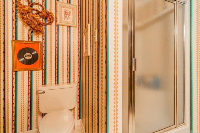 bathroom featuring toilet and a shower with shower door