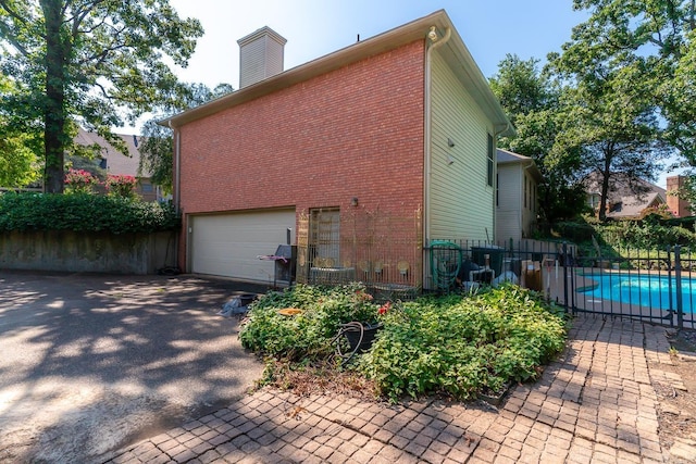 view of side of property with a garage and a fenced in pool