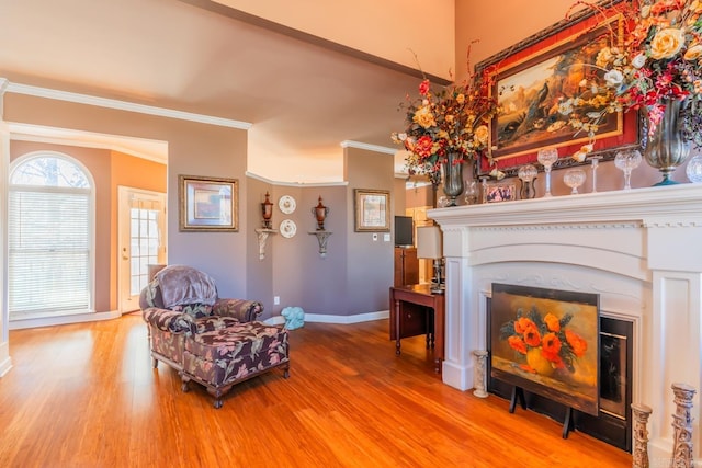 sitting room with a premium fireplace, light wood-type flooring, and crown molding