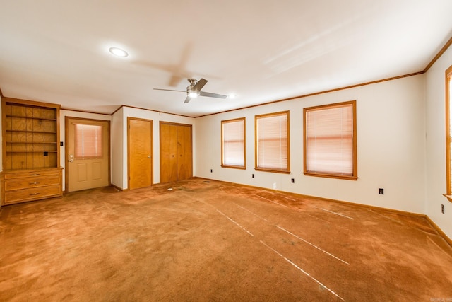 unfurnished bedroom featuring carpet floors, two closets, ceiling fan, and crown molding