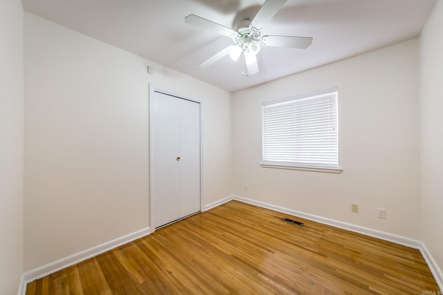 unfurnished bedroom with wood-type flooring, a closet, and ceiling fan