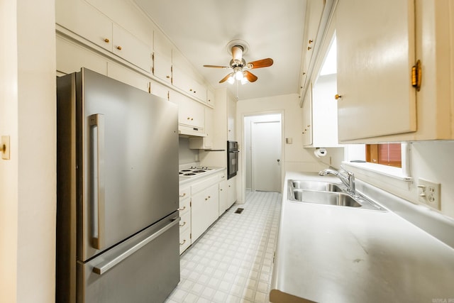 kitchen with sink, white cabinetry, black oven, stainless steel refrigerator, and white electric stovetop