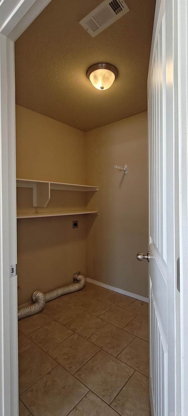 clothes washing area featuring electric dryer hookup and tile patterned floors